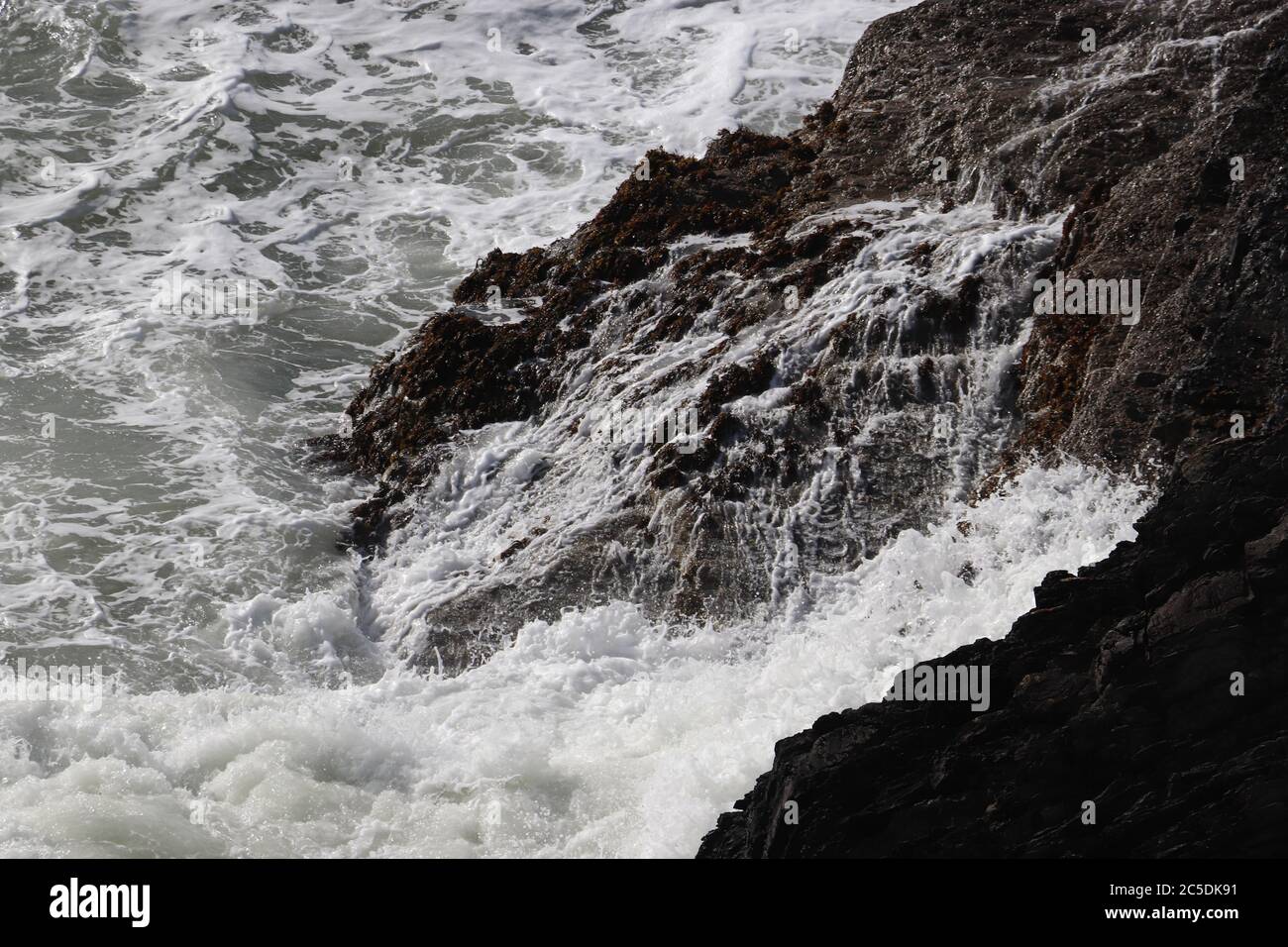 Rochers côtiers noirs entourés d'une mer en effervmer Banque D'Images