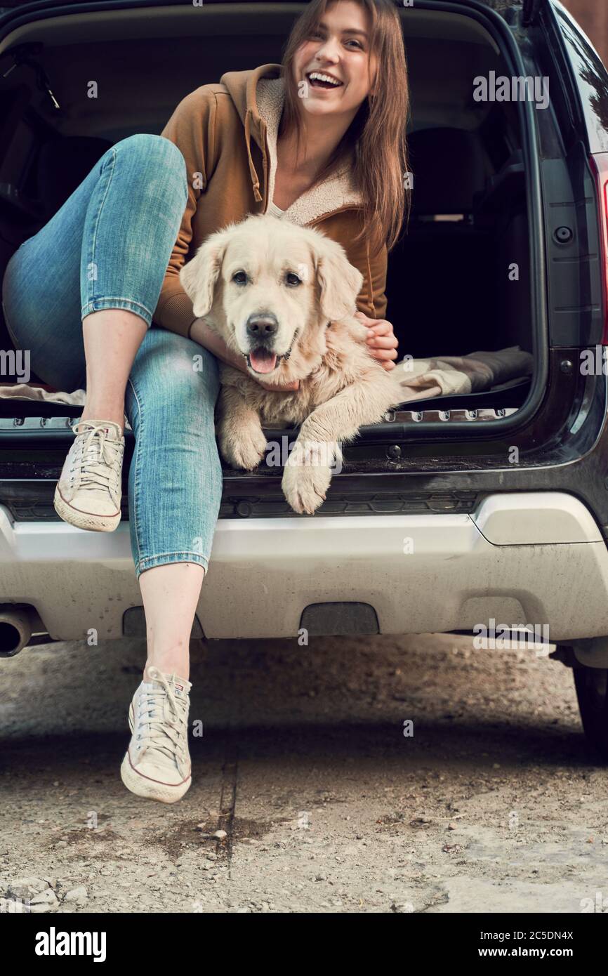Une femme heureuse encadre un châtiment en or assis dans le coffre ouvert de voiture noire Banque D'Images