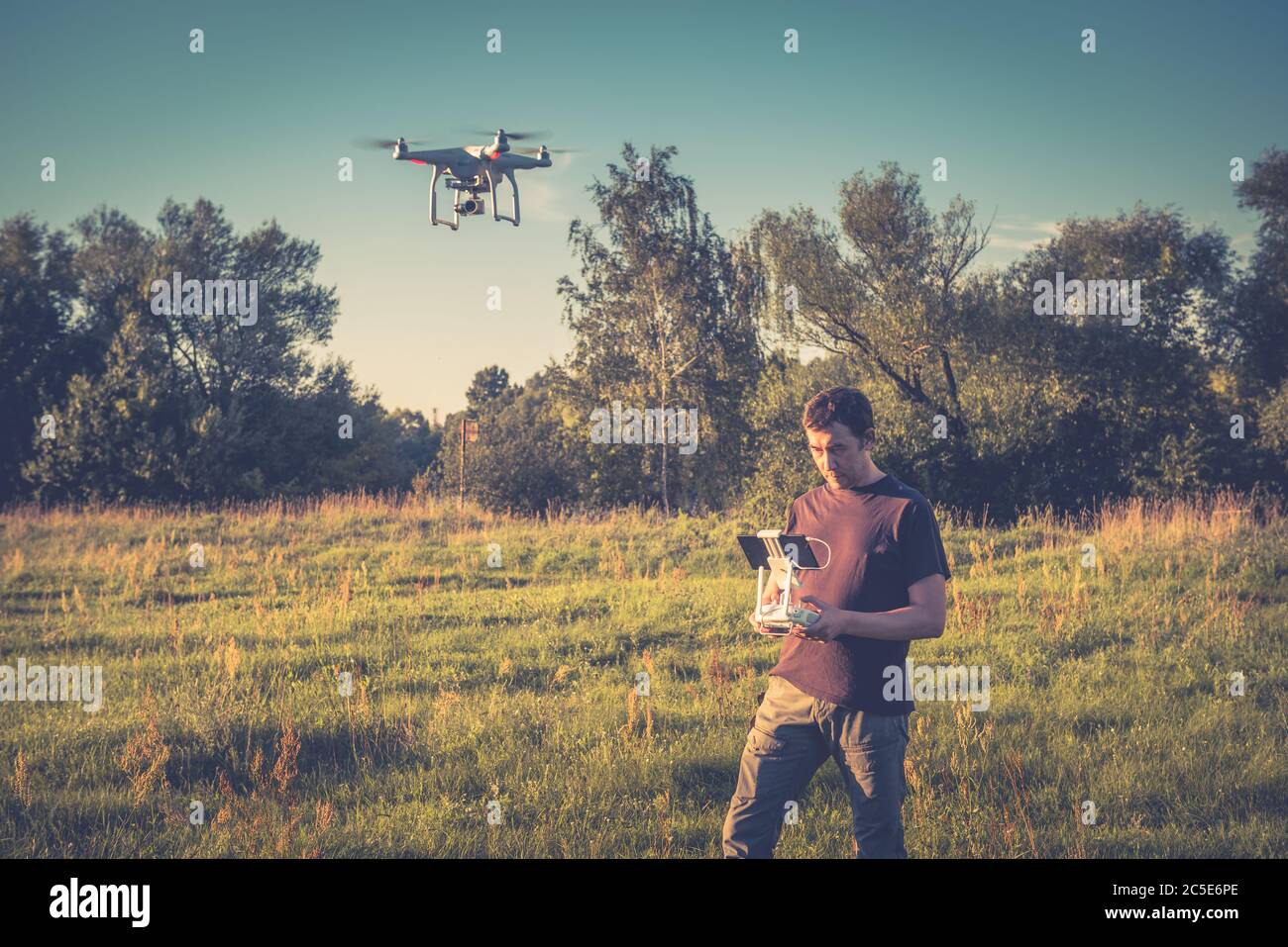 Homme utilisant un drone quad copter avec caméra numérique embarquée dans un parc Banque D'Images