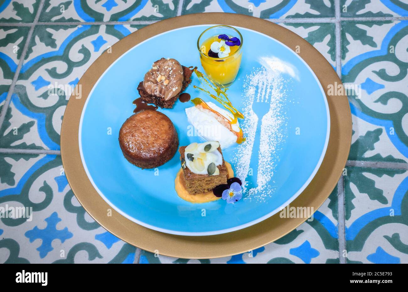 Brownie au chocolat, pudding à la malva, gâteau aux épices à la citrouille  avec glaçage glacé et caillé au citron dans un petit verre sur une assiette  bleue avec décoration de sucre