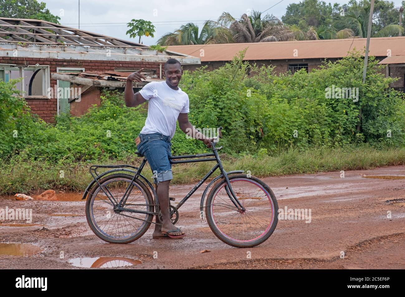Cycliste local qui longe la route boueuse de terre dans le village de Lehem pendant la saison des pluies, région de Takutu-haute Essechibo, Guyana, Amérique du Sud Banque D'Images