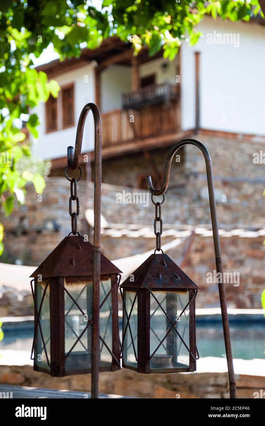 Les lampes de lanternes rouillées anciennes sur une table extérieure en bois comme décoration de jardin dans la maison traditionnelle de style de l'architecture de renouveau National en Bulgarie Banque D'Images