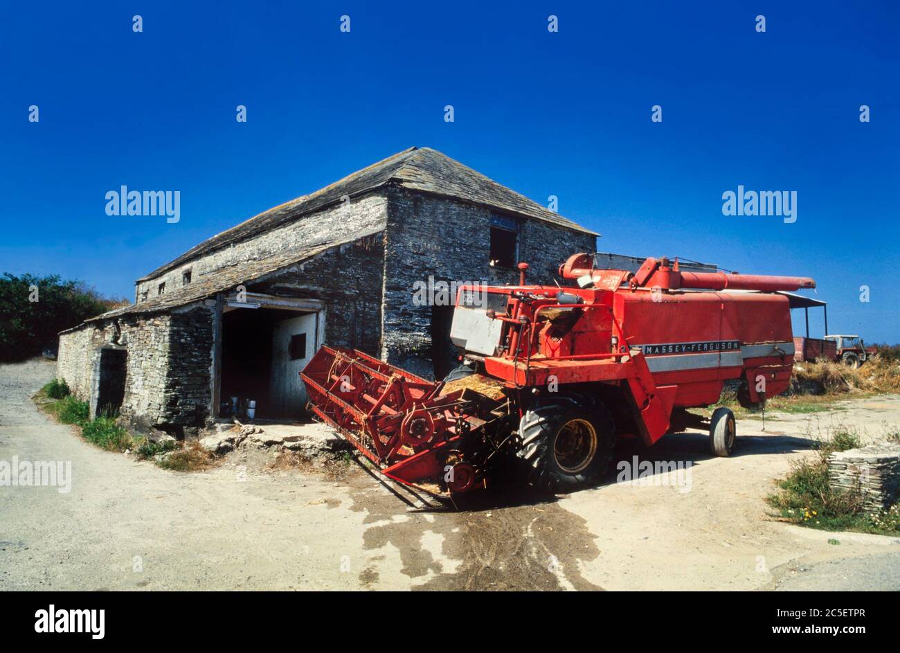 Moissonneuse-batteuse avec des bâtiments de ferme, ciel bleu Banque D'Images