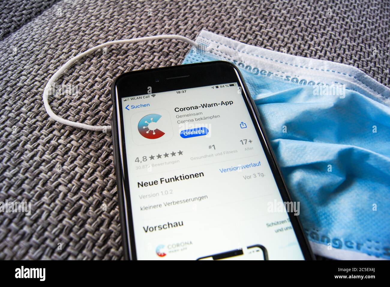 Corona Warn App du gouvernement fédéral allemand dans l'App Store d'Apple sur un smartphone portant un masque de protection. Banque D'Images