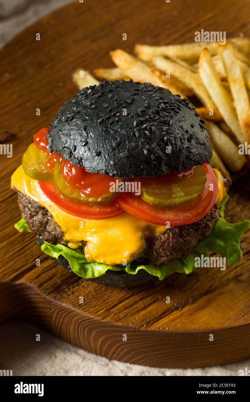 Cheeseburger maison avec un pain et des frites au charbon de bois noir Banque D'Images