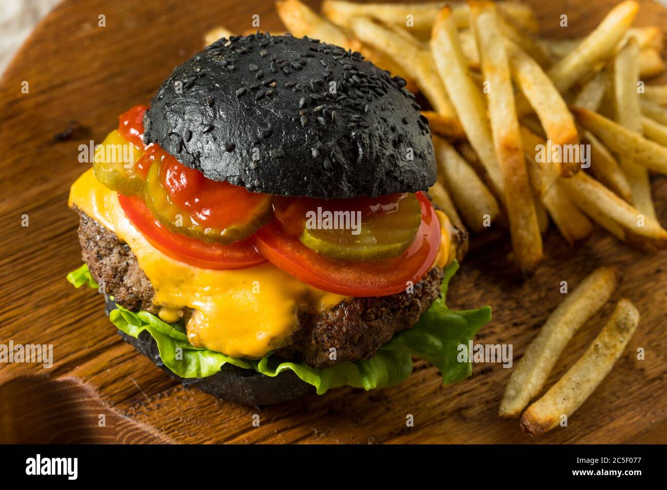 Cheeseburger maison avec un pain et des frites au charbon de bois noir Banque D'Images