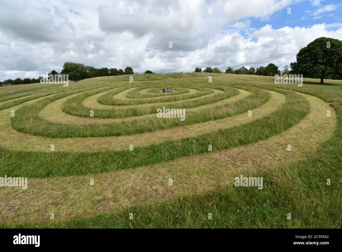 Les enfants jouent au centre de la trajectoire en spirale coupée dans l'herbe sur l'ancien champ d'exposition de fromage à Frome Somerset.UK Banque D'Images