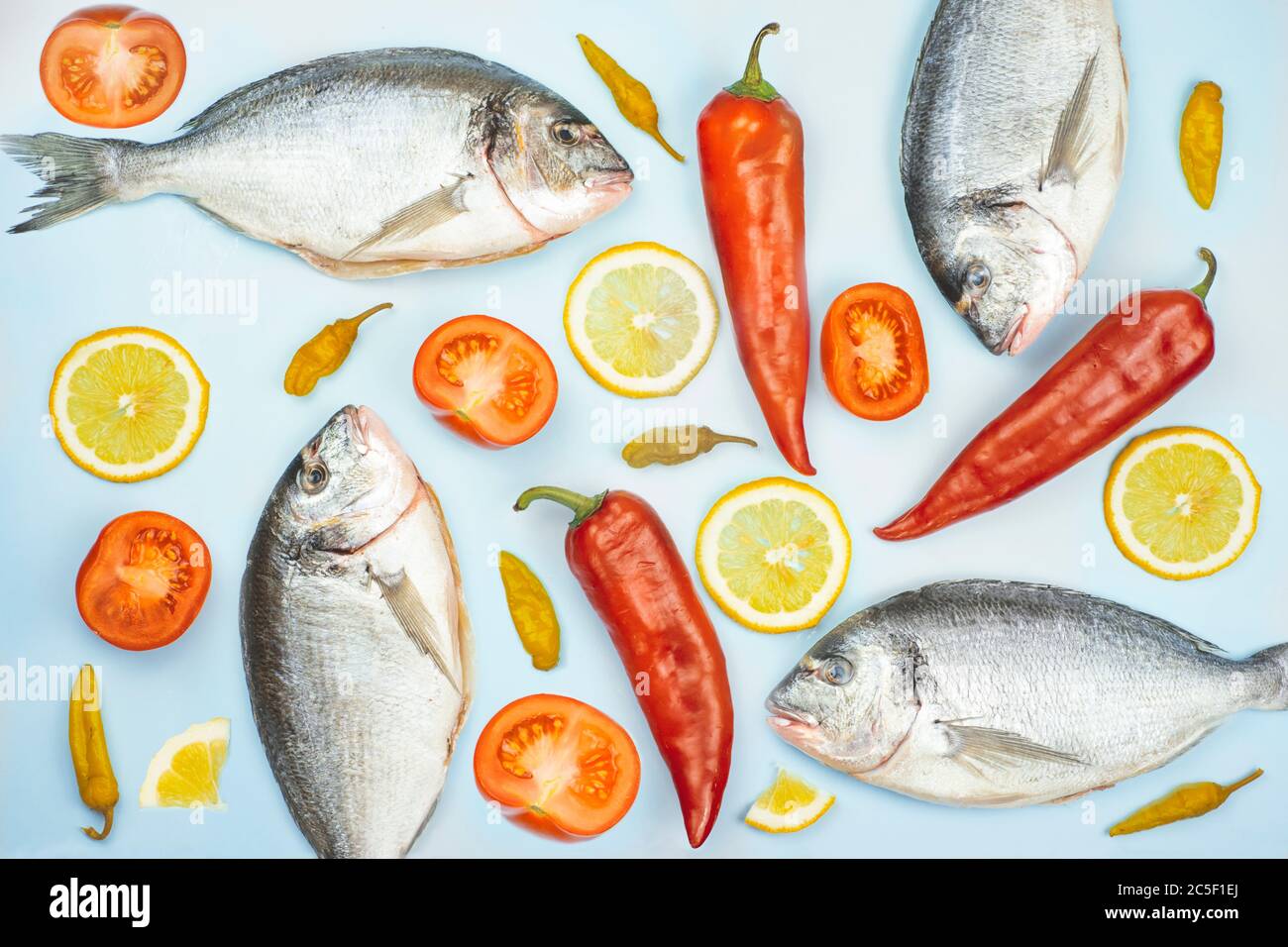 Poisson et légumes Dorado : concombre, tomate, poivre, citron sur fond bleu. Texture de fond pour la cuisine Banque D'Images