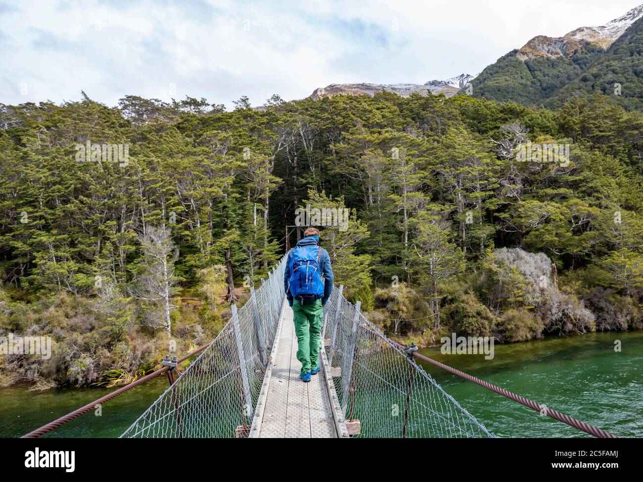 Jeune homme sur un pont suspendu au-dessus de la rivière Mavora, Mavora, Southland, South Island, Nouvelle-Zélande Banque D'Images