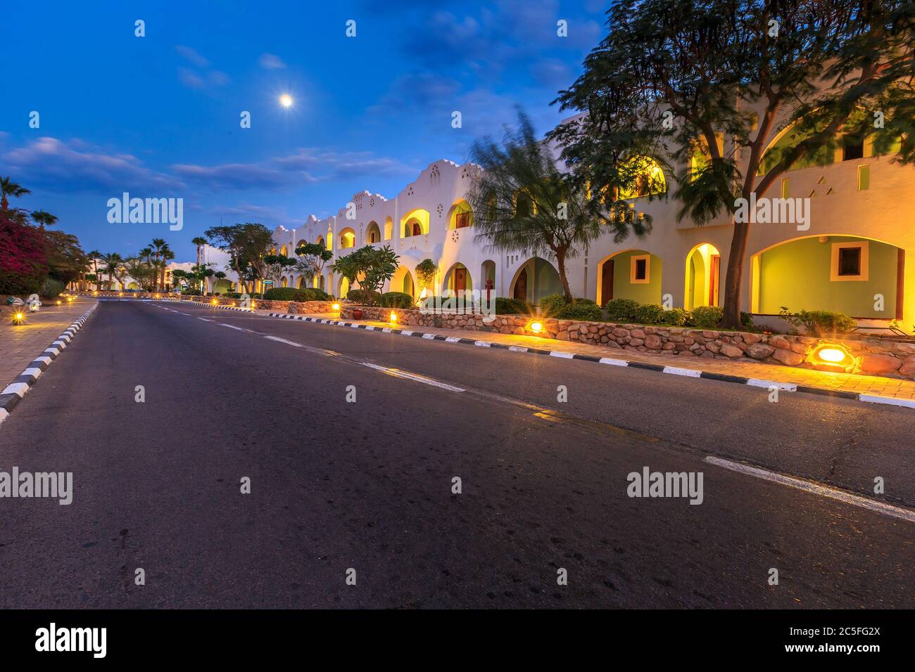 Vue en soirée pour l'éclairage de la route, appartements blancs, palmiers Banque D'Images