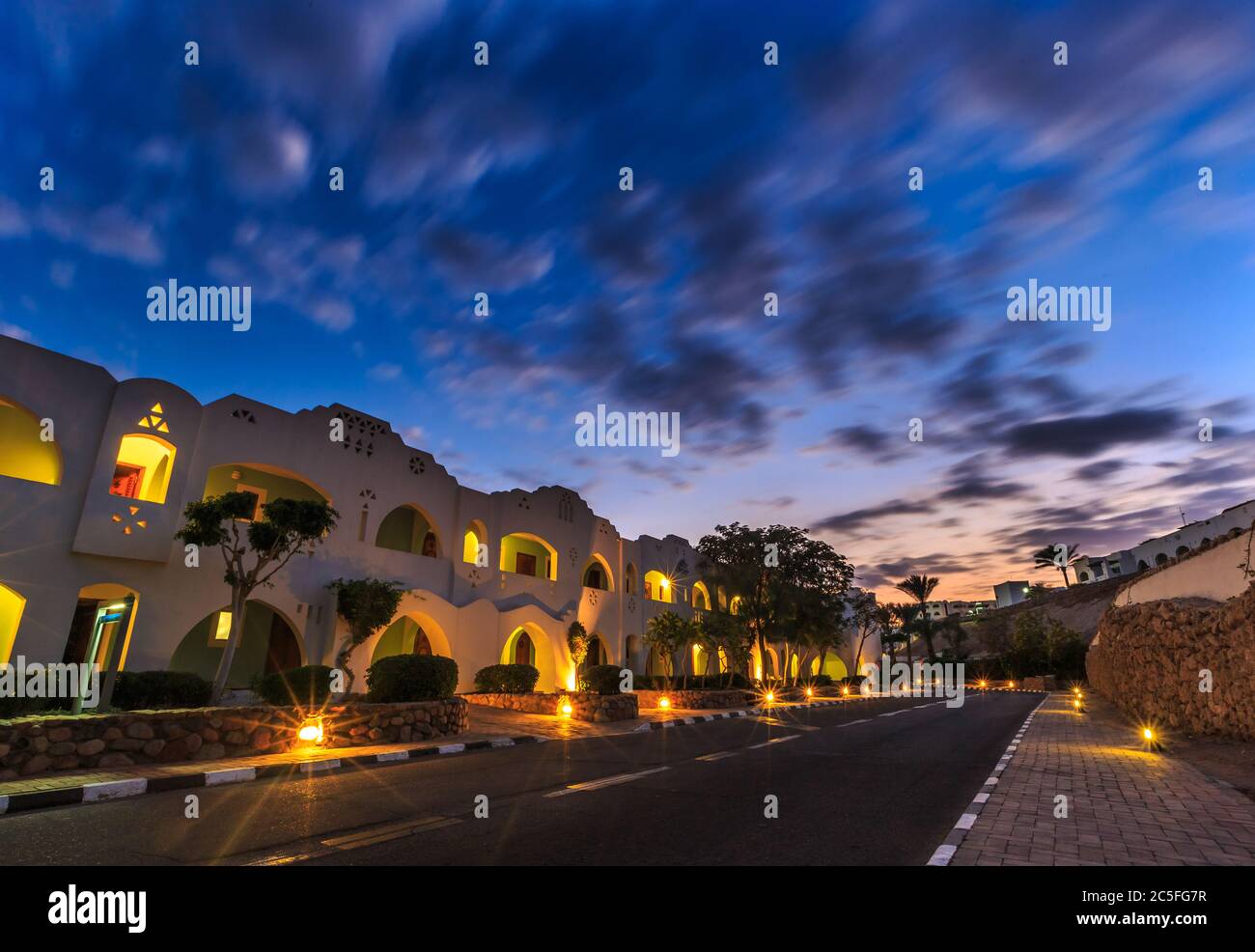 Vue en soirée pour l'éclairage de la route, appartements blancs, palmiers Banque D'Images