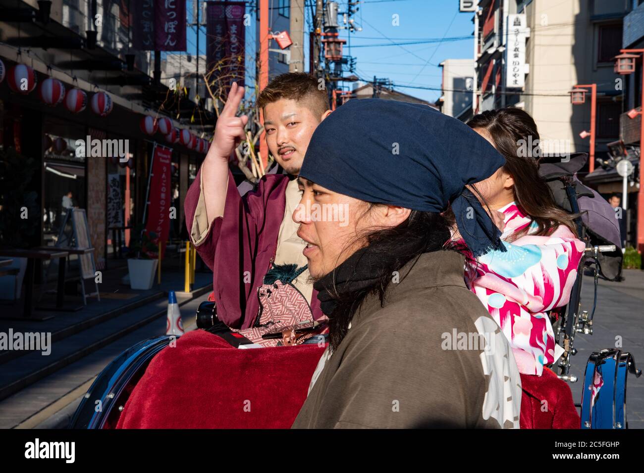 Portrait d'un conducteur de pousse-pousse avec un jeune couple de touristes sur son véhicule lors d'une visite touristique à Asakusa. Tokyo, Japon. Banque D'Images