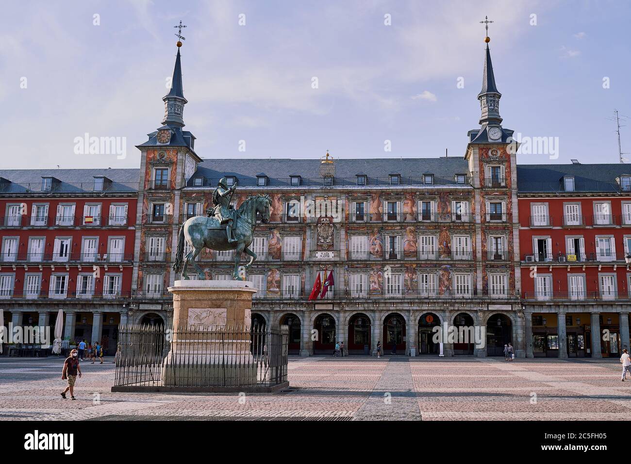 Plaza Mayor de Madrid, Espagne avec peu de gens, un homme portant un masque passe par la statue équestre de bronze du roi Felipe III (Philip III) Banque D'Images Plaza Mayor de Madrid, Espagne avec peu de gens, un homme portant un masque passe par la statue équestre de bronze du roi Felipe III (Philip III) Banque D'Images