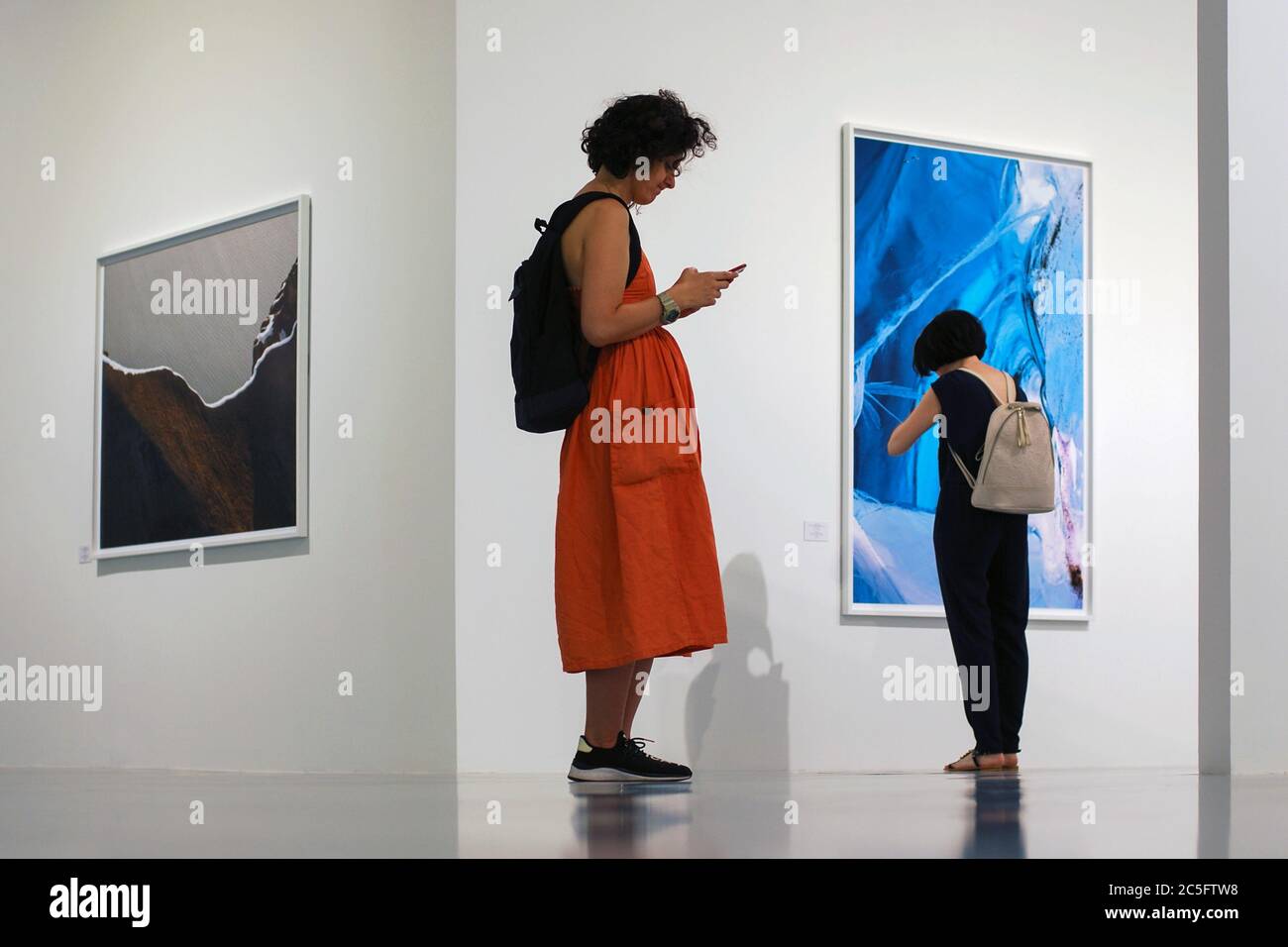 Moscou 11/06/2019 comportement des personnes à l'exposition de photos - une femme examine l'image sur le mur, l'autre est absorbé par la communication de réseau social Banque D'Images