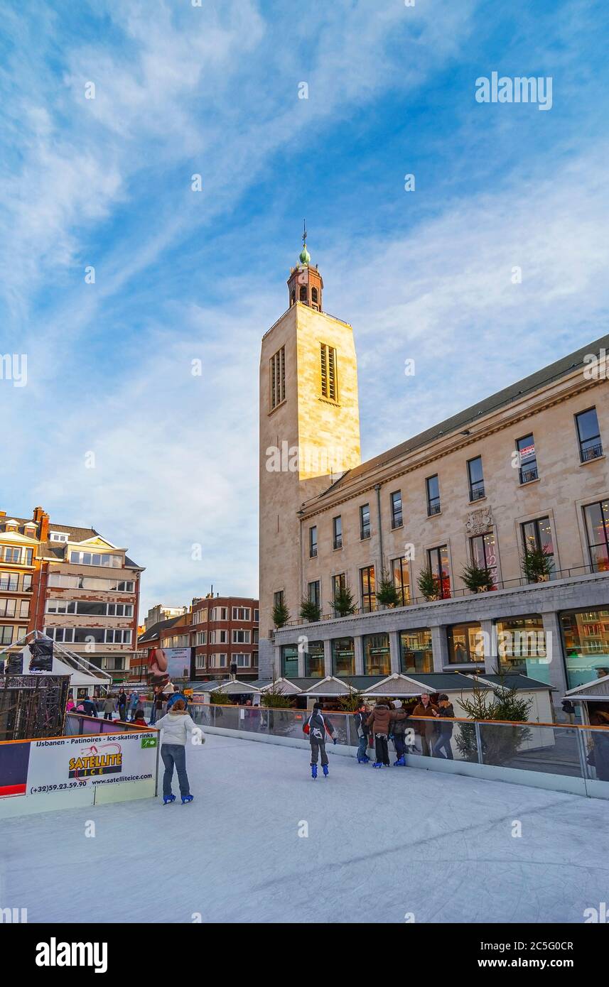 Les gens patinent sur le marché d'hiver et la place principale de la ville avec l'ancien palais culturel et de fête en arrière-plan, Ostende, Belgique. Banque D'Images