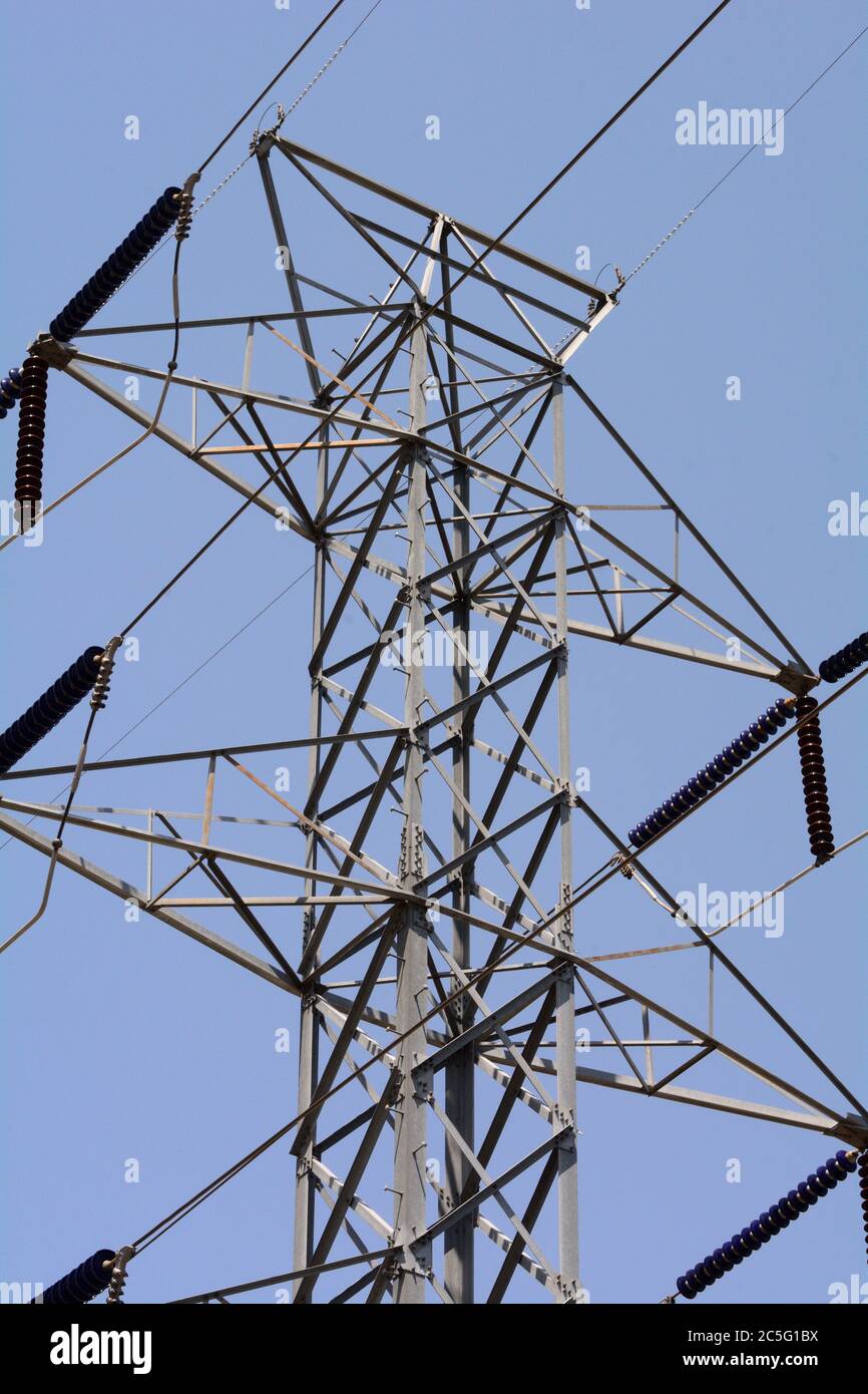 Gros plan de la tour de pylône électrique avec des isolateurs contre le ciel bleu clair Banque D'Images