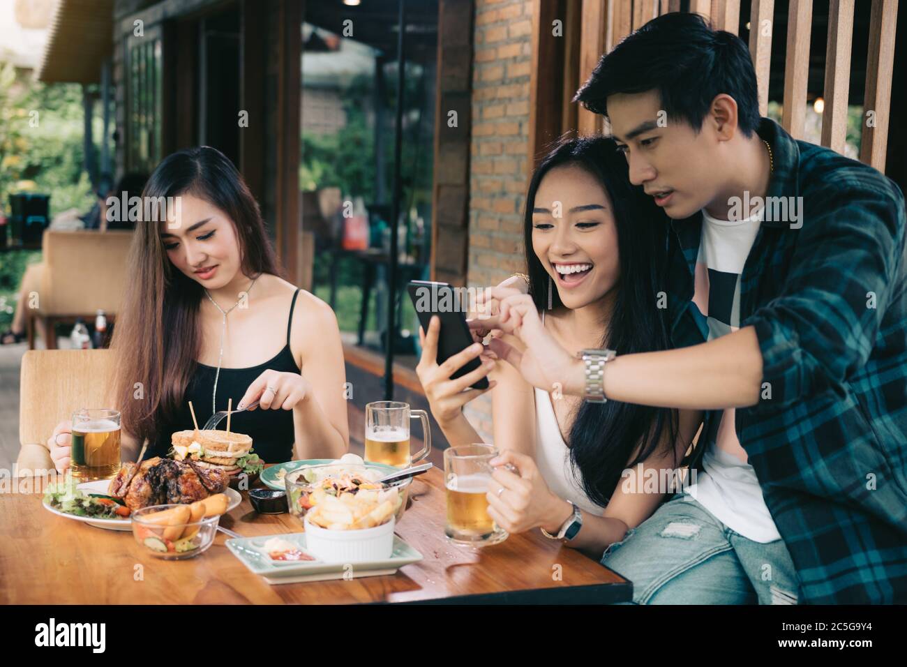 Femme asiatique unique enviant avec amour couple faire prendre selfie au restaurant. Banque D'Images