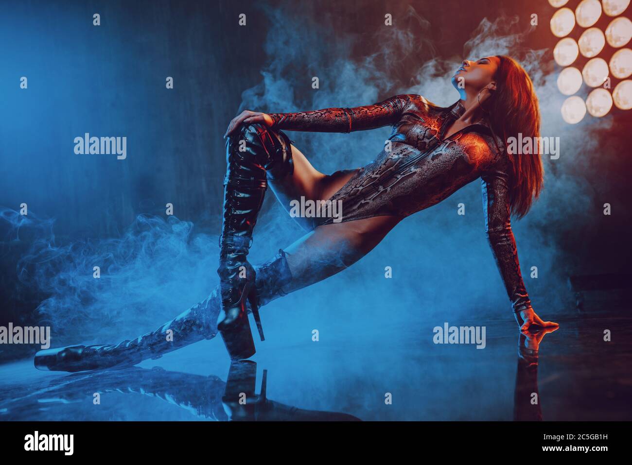 Jeune femme sexy danseuse posant en studio avec des lumières bleues et rouges Banque D'Images