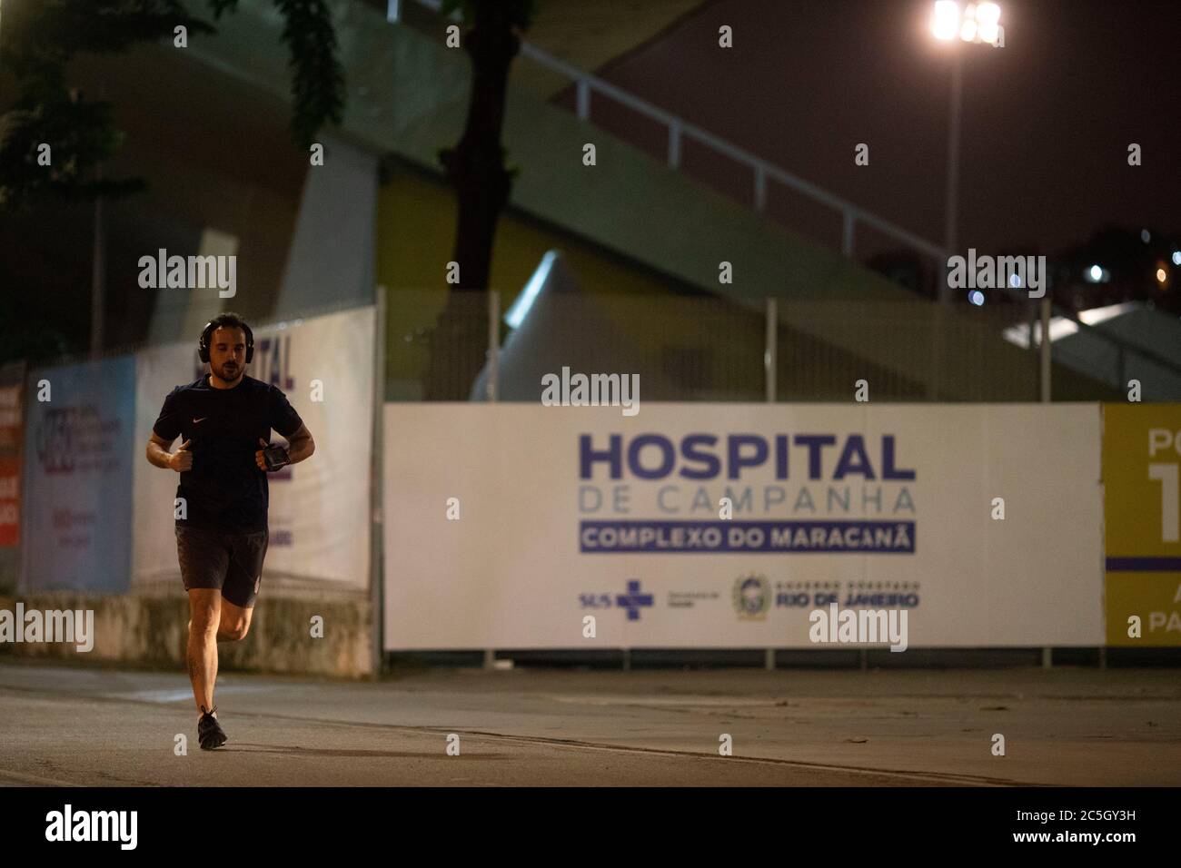 02 juillet 2020, Brésil, Rio de Janeiro : Un homme passe devant l'hôpital de Campanha Complexo do Maracana, en face du stade Maracanã, dans l'annexe où se trouve l'hôpital de campagne pour le traitement des patients de COVID19, lors du match de football de Volta Redonda X Resende pour le championnat national de football. Les matchs de football ont de nouveau eu lieu à Rio de Janeiro, le seul État du pays qui permet la reprise du sport, malgré le nombre élevé d'infections et de décès causés par la maladie, qui sont encore enregistrés quotidiennement dans l'État et le pays. Brésil REC Banque D'Images