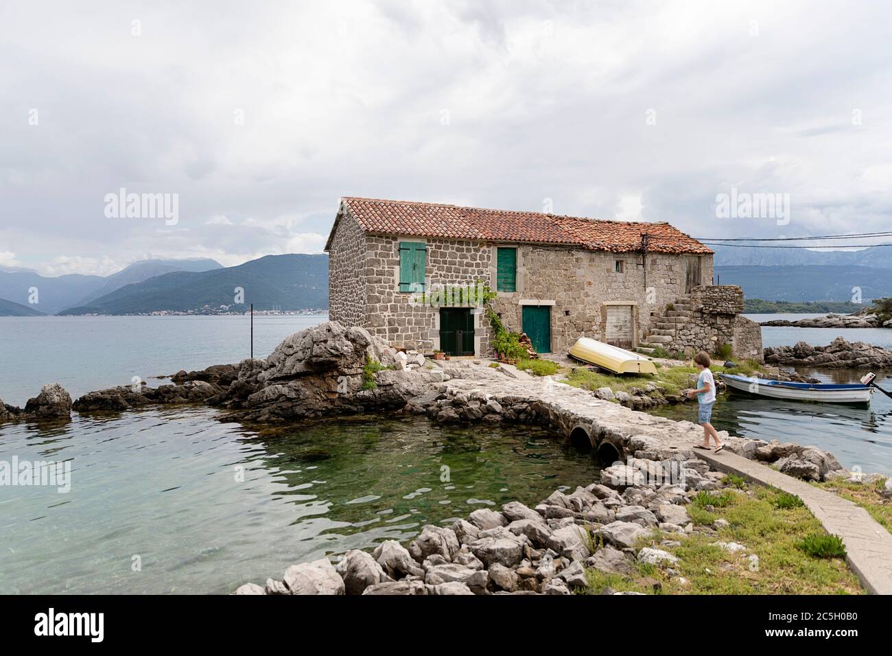 Garçon marchant vers une maison de pêcheurs, Maison sur l'île, Bjelila, Lustica, Boka Kotorska, Monténégro Banque D'Images