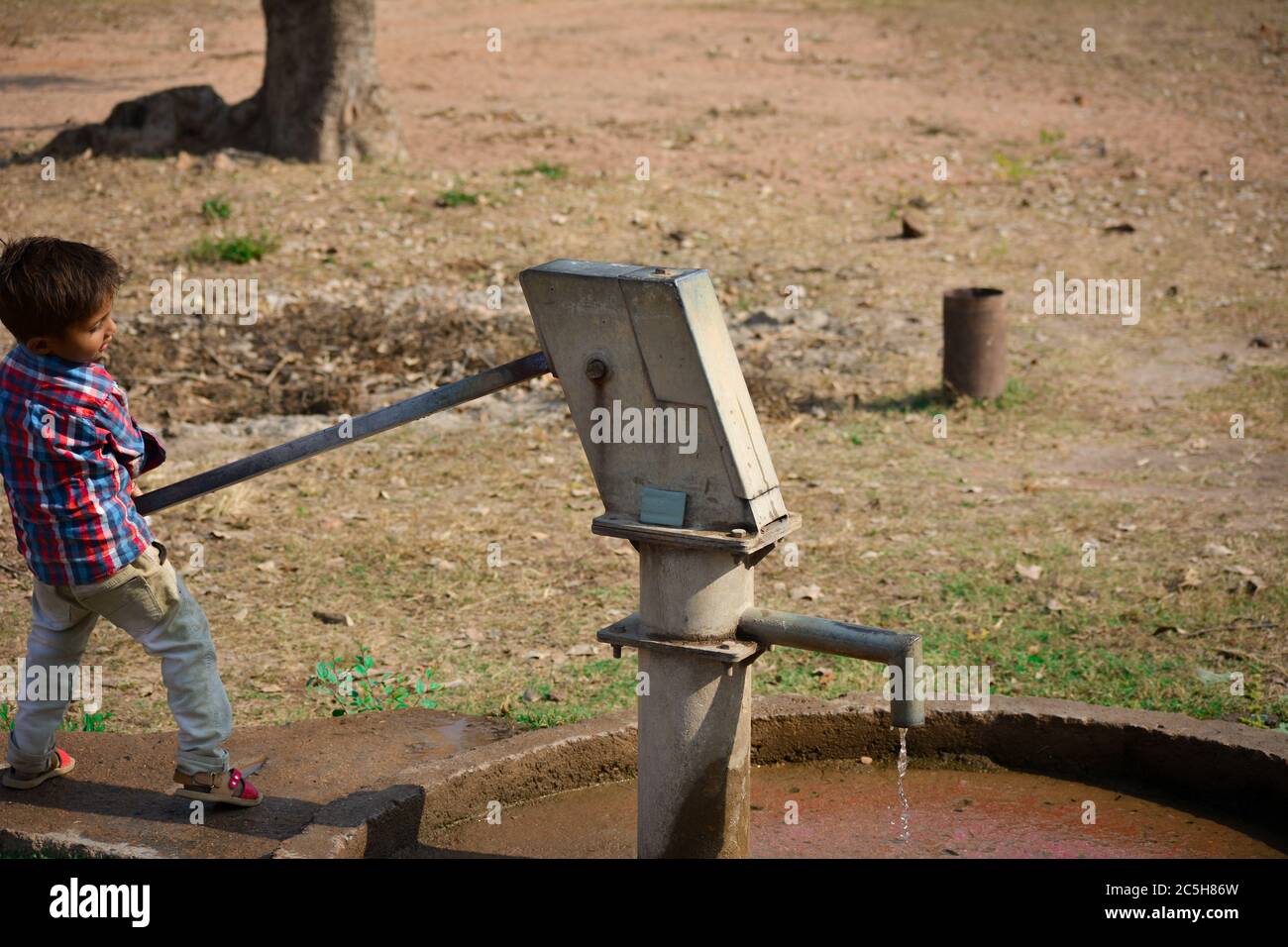 TIKAMGARH, MADHYA PRADESH, INDE - 20 NOVEMBRE 2019 : petit garçon non identifié de village indien pompant pompe à eau manuelle. Banque D'Images