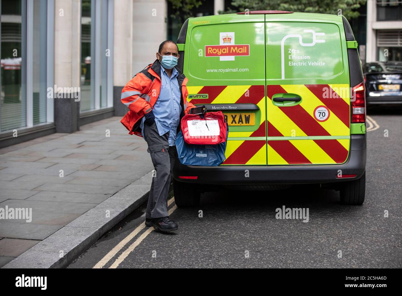 Employé de livraison postale se préparant à charger son Royal Mail Zero Emission Electric postal Van portant un masque facial dans le centre de Londres, Angleterre, Royaume-Uni Banque D'Images