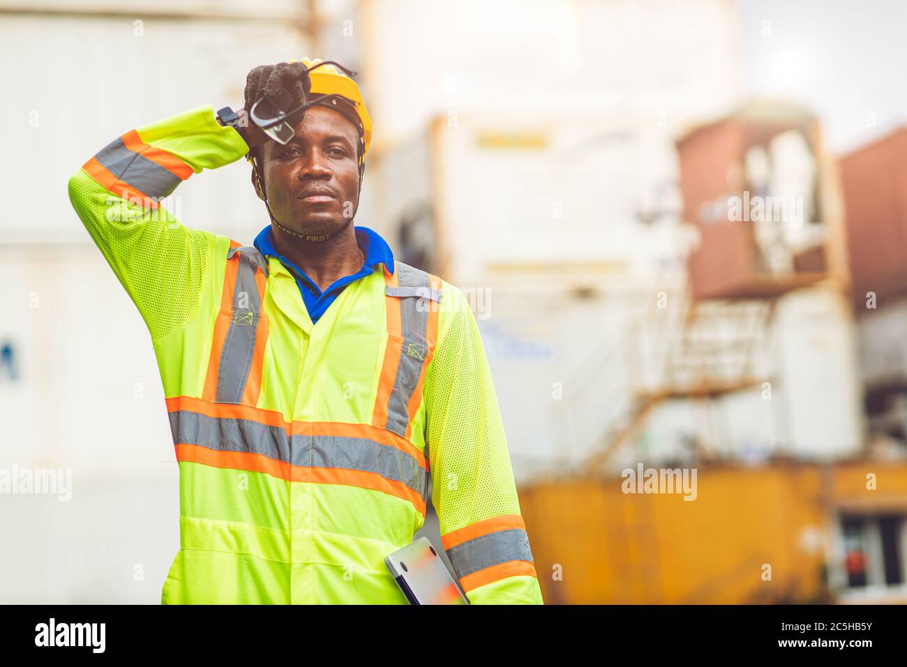 Travailleur de stress fatigué sueur par temps chaud en été travaillant dans le port marchandises fret maritime logistique terrain, Black African race People. Banque D'Images