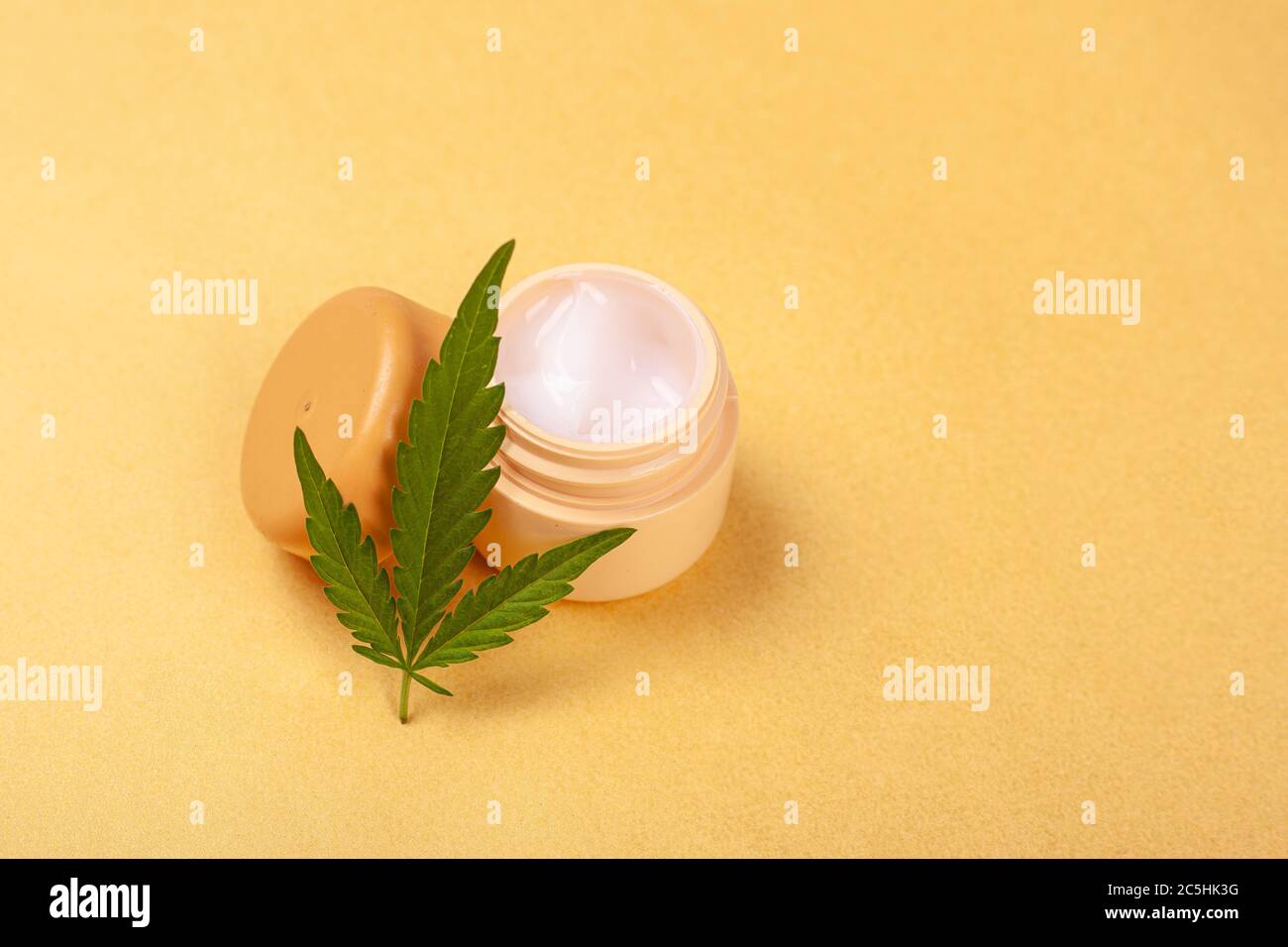 beauté, soins de la peau cosmétiques avec extrait de marijuana. crème pour le visage avec une feuille de cannabis vert sur fond jaune gros plan. Banque D'Images