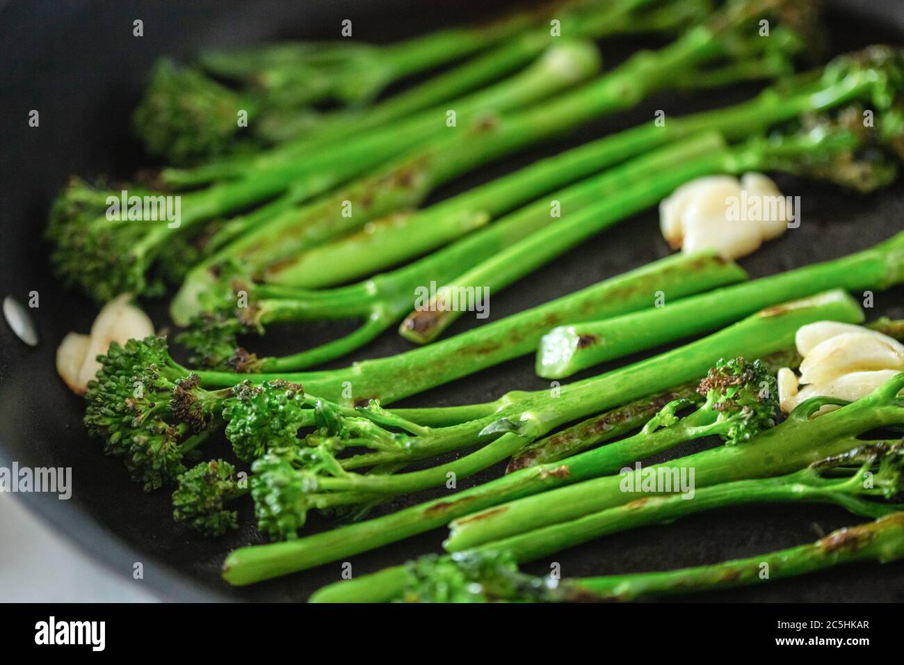 Cuisson du broccolini dans une poêle à frire. Vue en angle, gros plan. Banque D'Images