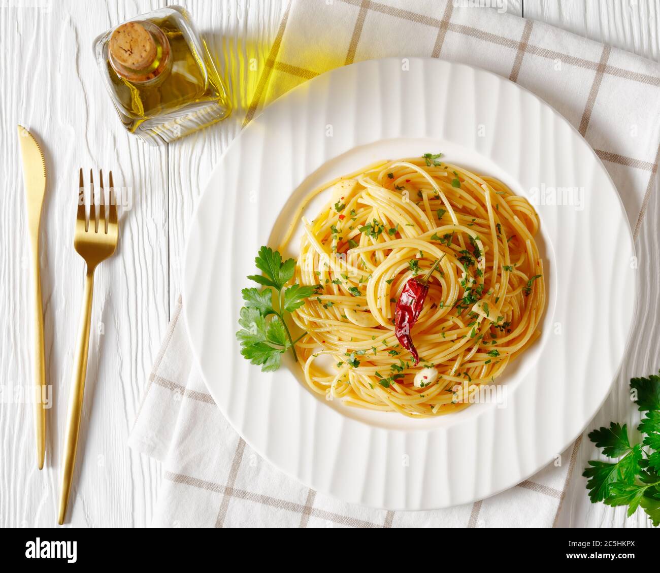 Spaghetti Alla colatura di alici, spaghetti à la sauce anchois, piment, ail et persil sur une assiette blanche sur une table blanche en bois, horizonta Banque D'Images