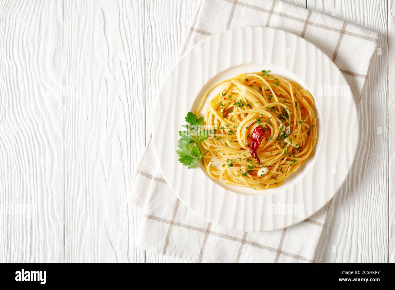 Spaghetti Alla colatura di alici, spaghetti à la sauce anchois, piment, ail et persil sur une assiette blanche sur une table blanche en bois, horizonta Banque D'Images