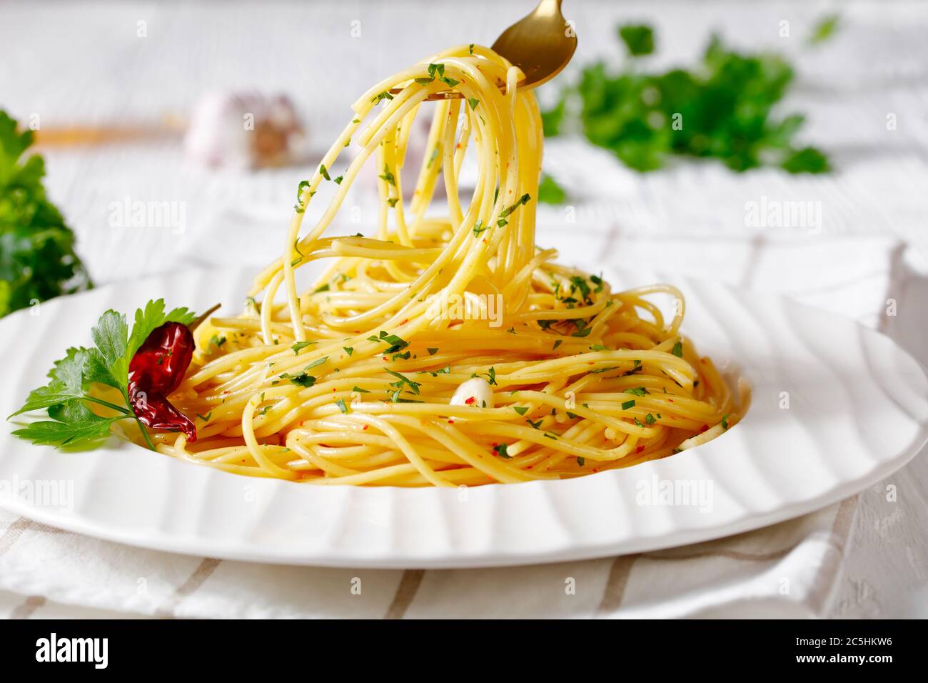 Spaghetti à la colatura di alici, spaghetti à la sauce anchois, piment, ail et persil sur une assiette blanche et sur une fourchette dorée, paysage Banque D'Images