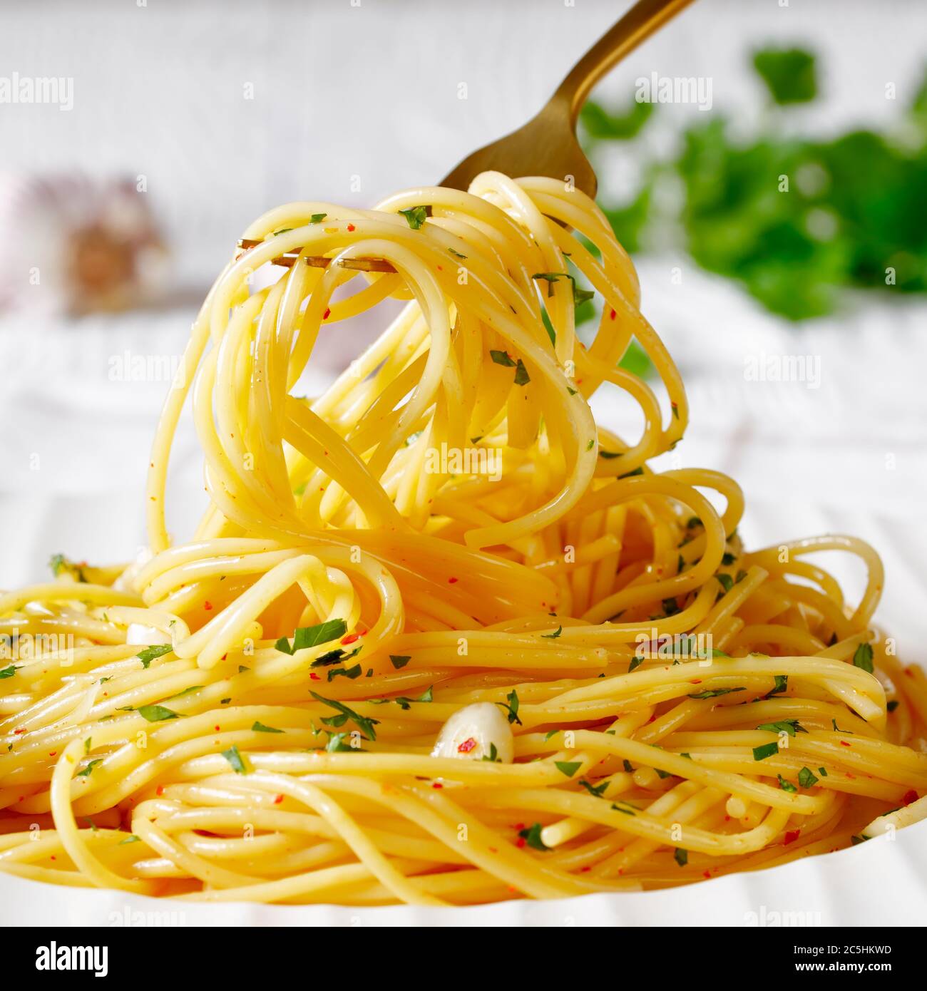 Spaghetti à la colatura di alici, spaghetti à la sauce anchois, piment, ail et persil sur une assiette blanche et sur une fourchette dorée, paysage Banque D'Images