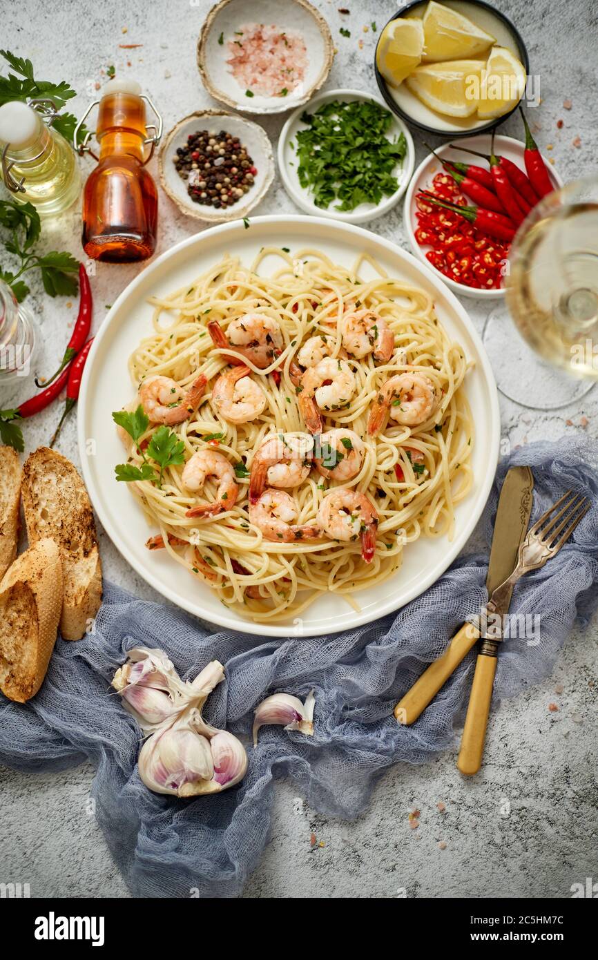Spaghetti aux crevettes sur plaque de céramique blanche et servis avec un verre de vin blanc Banque D'Images