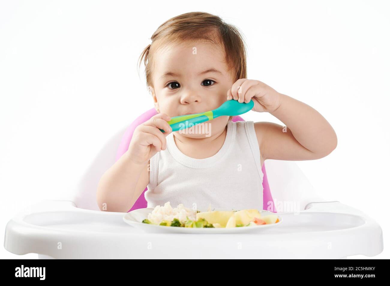 Jolie petite fille avec cuillère devant l'assiette avec nourriture Banque D'Images