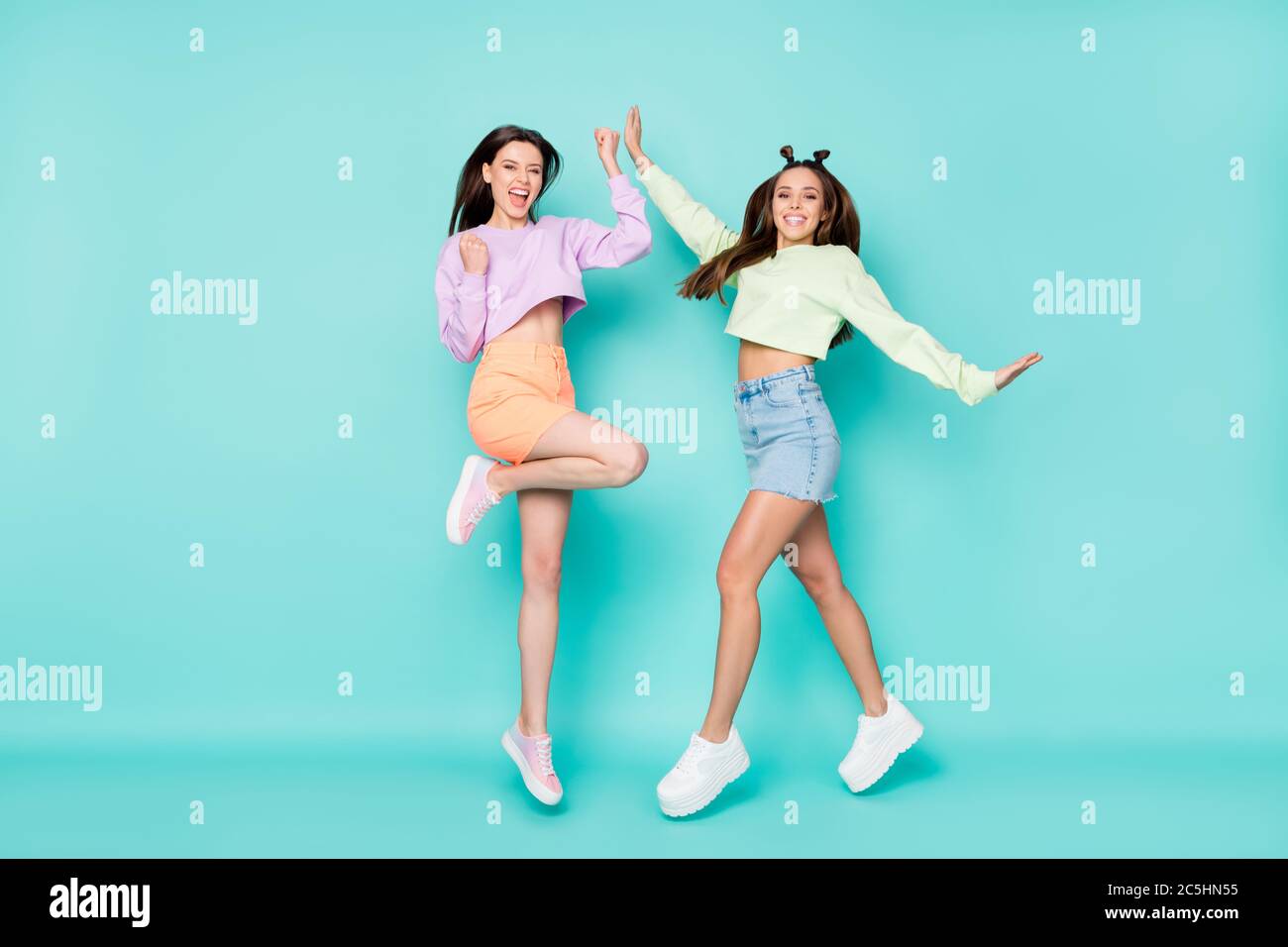 Photo pleine grandeur de deux jolies sœurs fous sauter haut vêtements  jeunes se réjouir étudiants fête vêtements pantacourts chandails courtes  jupes chaussures isolées Photo Stock - Alamy