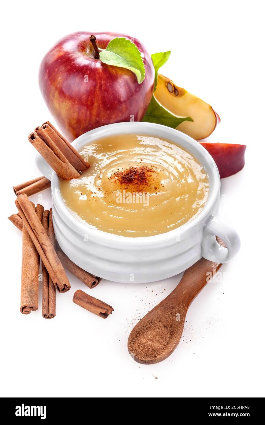 Purée de pommes ou sauce dans un plat blanc en céramique avec de la cannelle et des tranches de pommes. Isolé sur blanc. Le concept de saine alimentation et de mode de vie. Banque D'Images