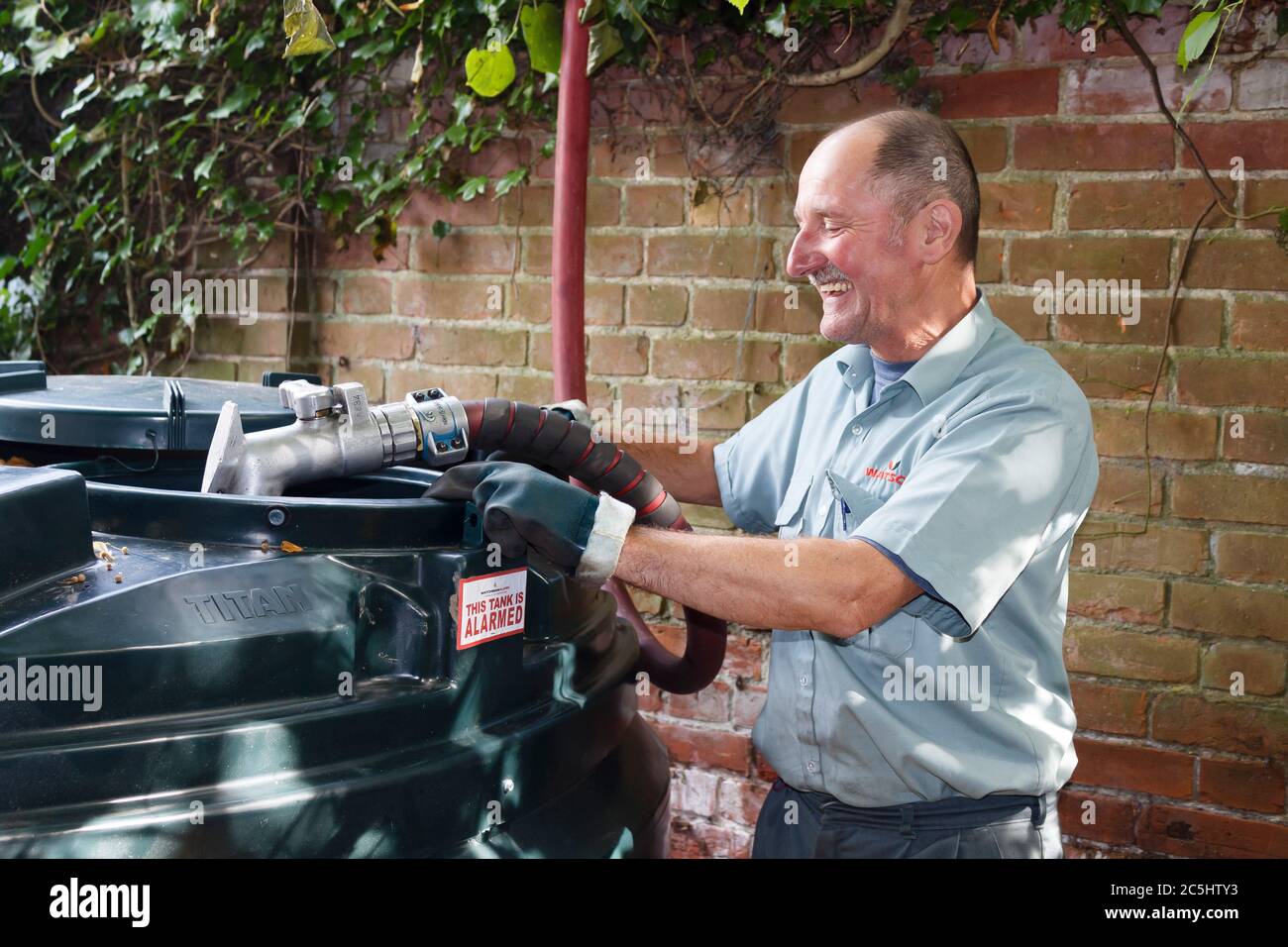 BUCKINGHAM, Royaume-Uni - 13 septembre 2014. Homme remplissant un réservoir d'huile bondé avec de l'huile de chauffage domestique (kérosène) dans une maison dans la campagne anglaise, Royaume-Uni Banque D'Images