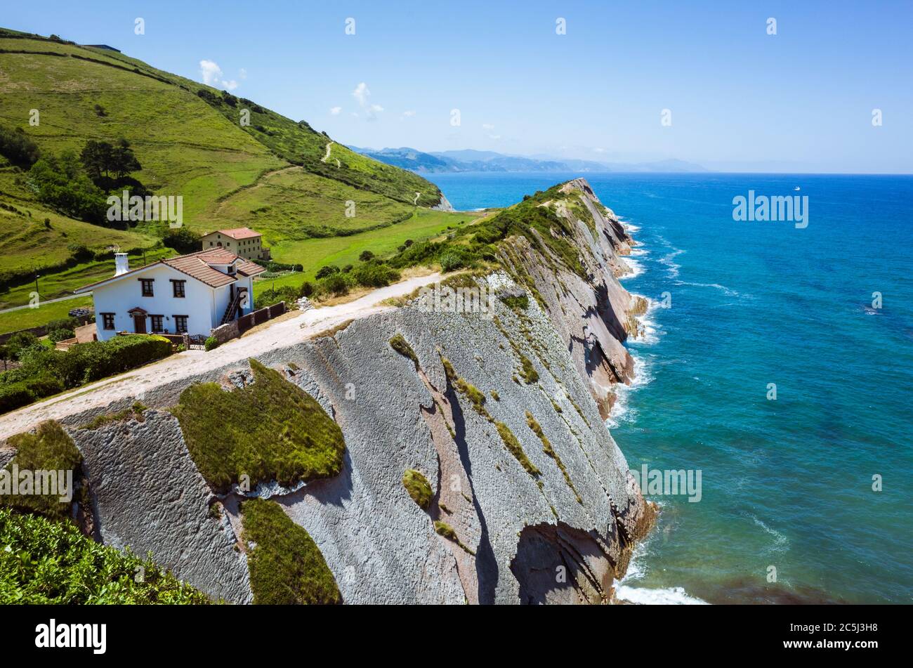 Zumaia, Gipuzkoa, pays Basque, Espagne - 15 juillet 2019 : maison de campagne au sommet de la falaise en roche de flysch sur la plage d'Itzurun. Banque D'Images
