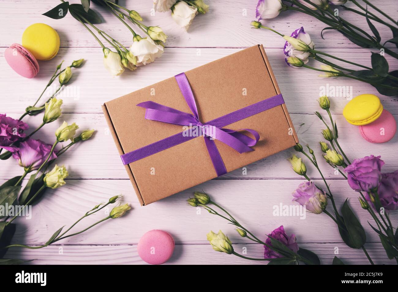 boîte cadeau avec fleurs et macarons sur fond de bois blanc. carte de vœux pour l'anniversaire, le jour de la mère ou le jour de la saint-valentin Banque D'Images