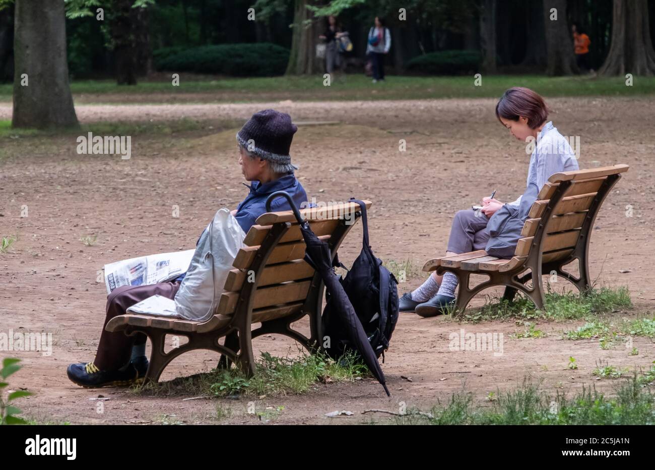 Un vieil homme sans abri et une jeune femme assis sur un banc en bois séparé. Banque D'Images