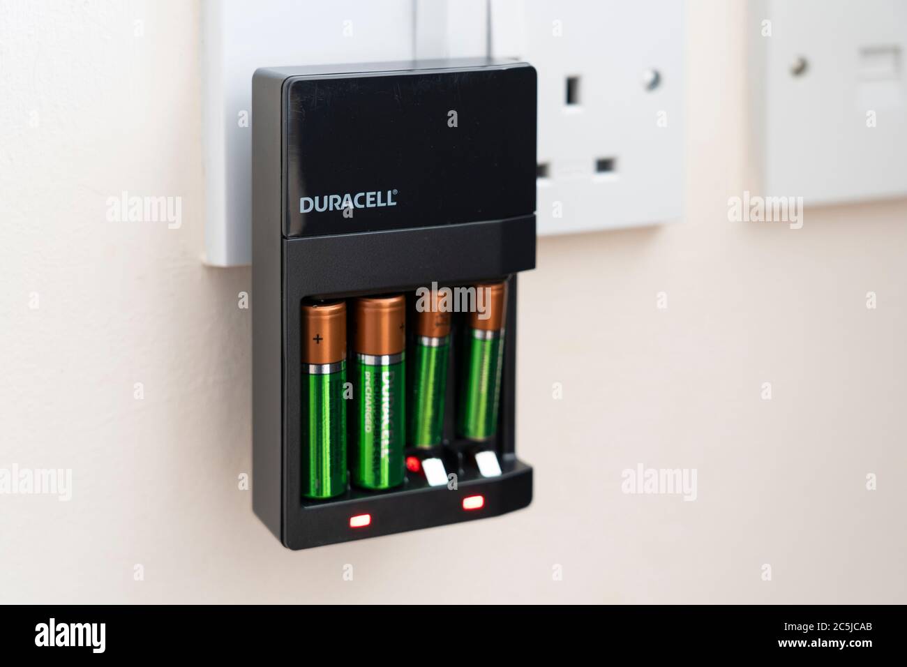 Un chargeur de batterie rechargeable Duracell branché dans une prise avec des piles AA et AAA réutilisables en charge dans une maison britannique Banque D'Images