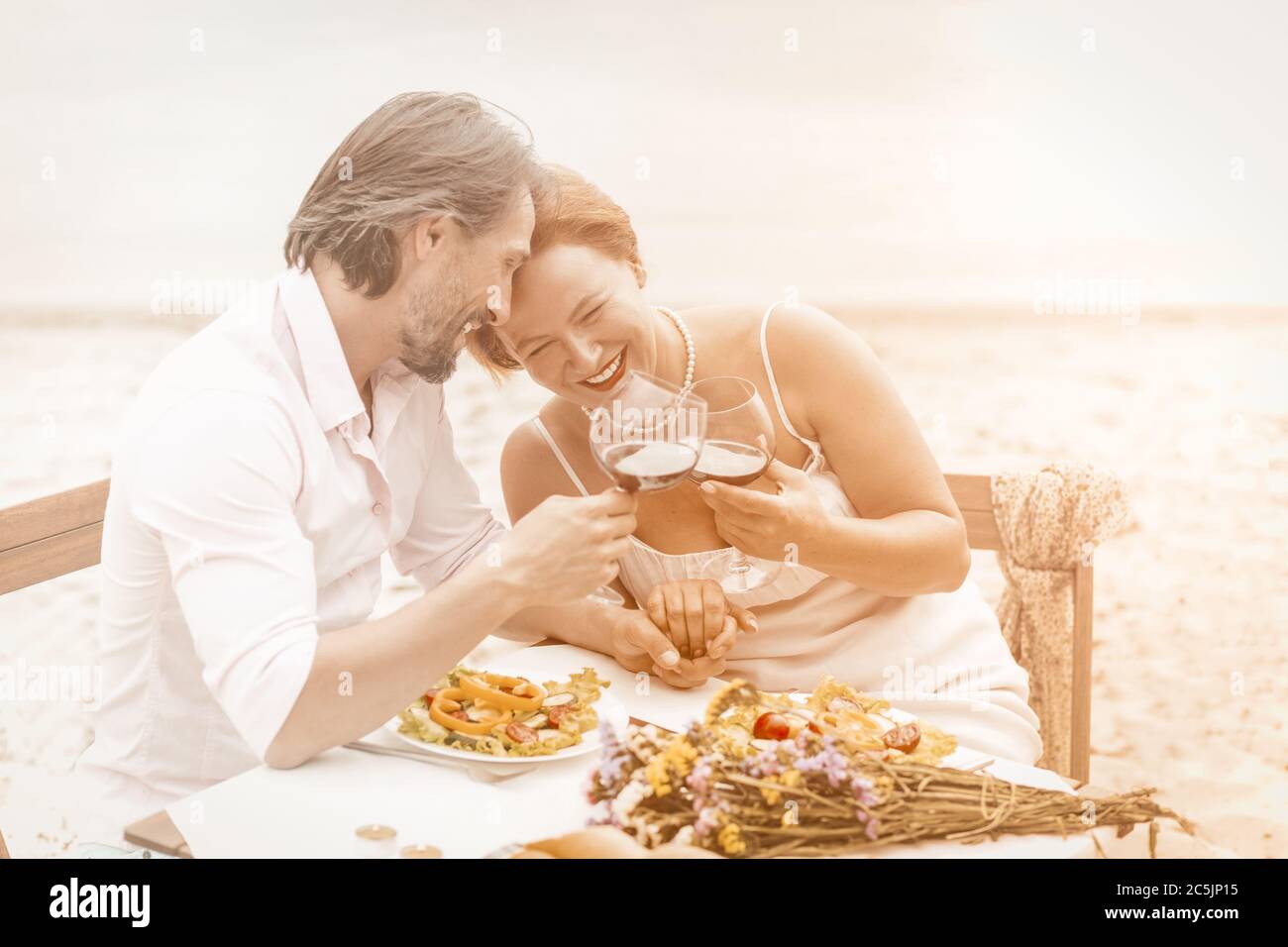 Charmant couple d'âge mûr buvant du vin au bord de la mer. Deux personnes caucasiennes souriantes passent du temps ensemble dans un café de plage. Concept d'amour. Concept anniversaire Banque D'Images