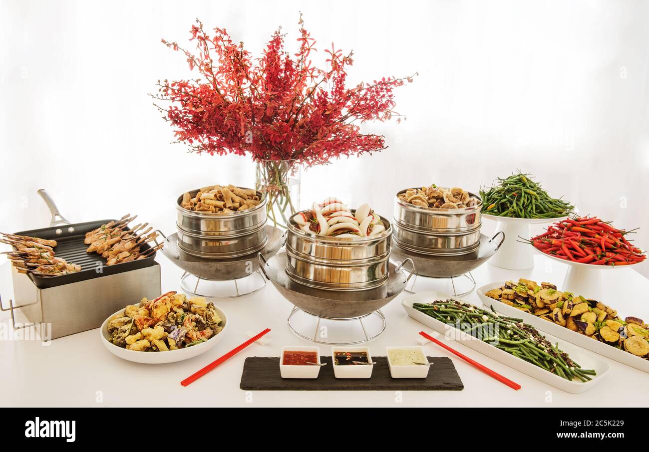 Buffet asiatique avec potstickers, petits pains au porc, rouleaux de printemps, brochettes, aubergines, tempura et poivrons chauds Banque D'Images
