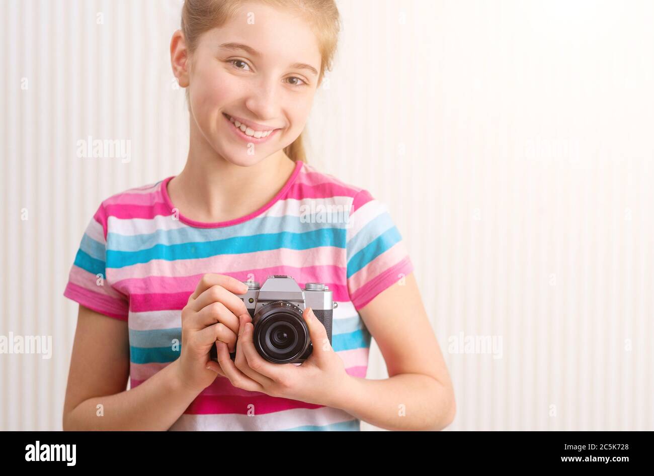 Bonne fille tenant un appareil photo en studio Banque D'Images