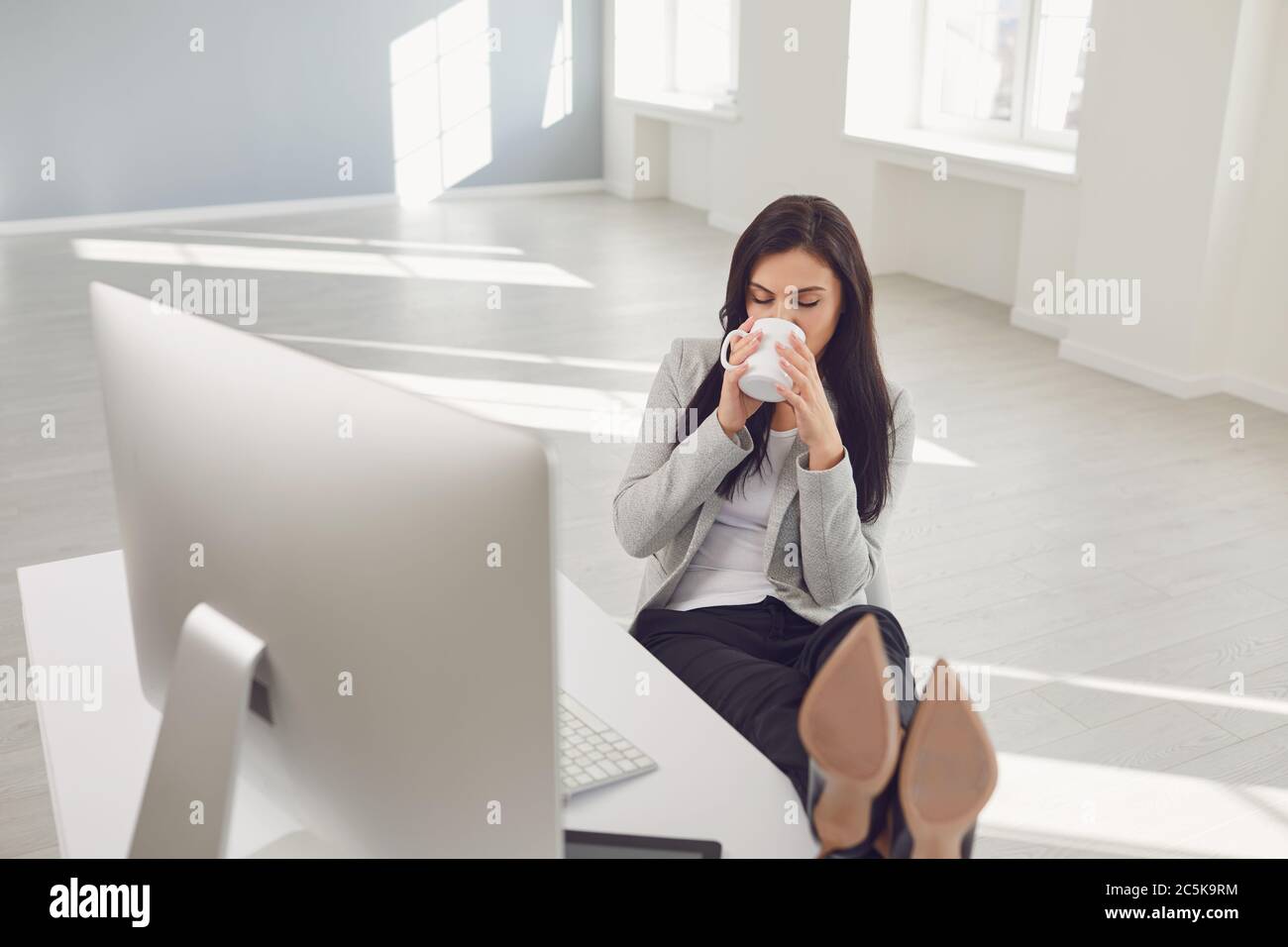 Femme d'affaires détenante qui apprécie un café sur le lieu de travail au bureau Banque D'Images