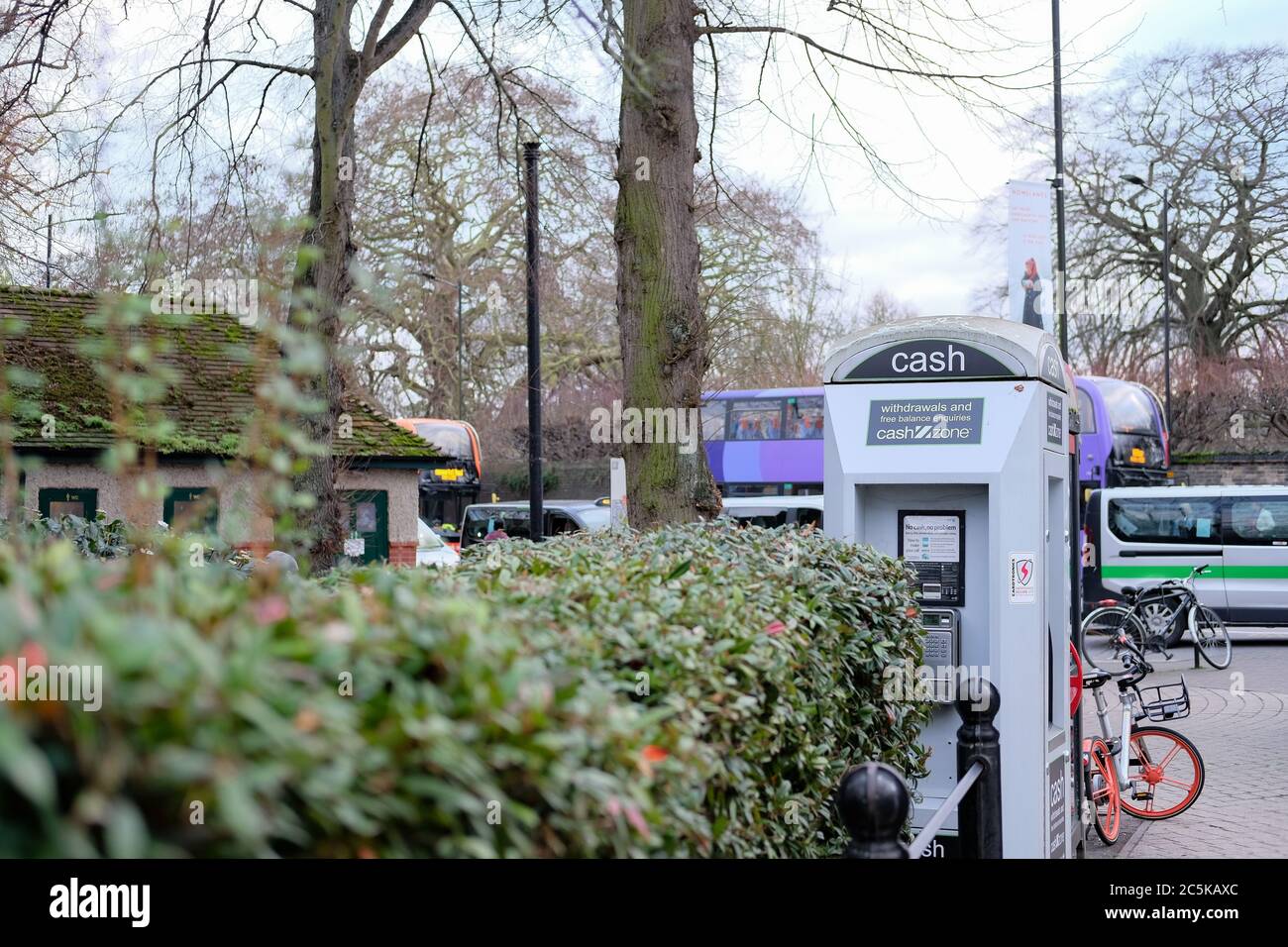 Distributeur de billets public blindé vu près d'une gare routière dans le centre-ville. Situé près d'une gare routière, les bus peuvent être vus en arrière-plan lors d'une journée chargée. Banque D'Images
