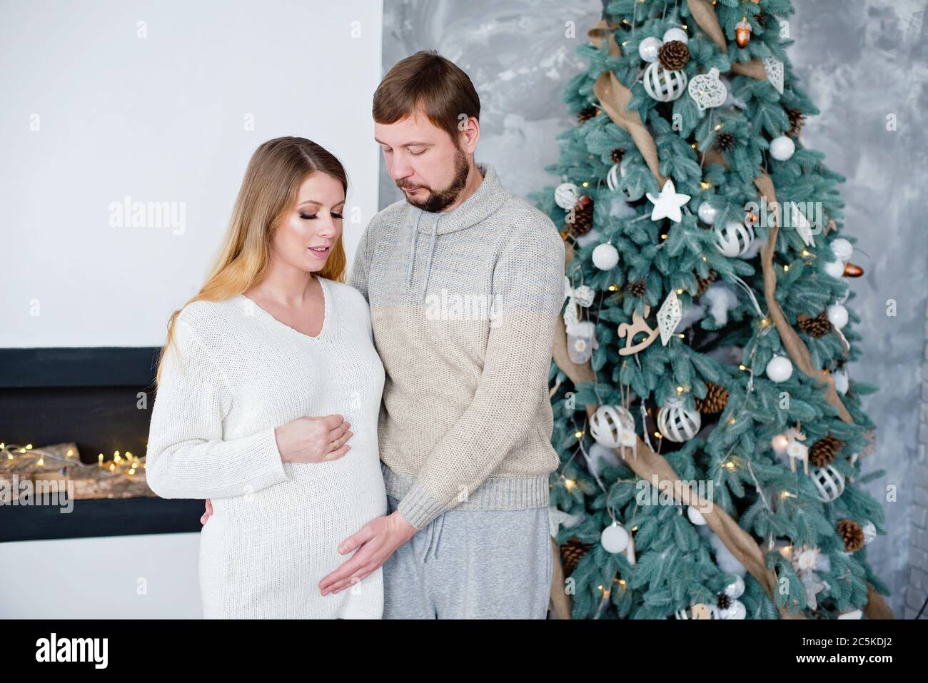 Jeune couple s'attendant à un bébé près de l'arbre de Noël. Femme