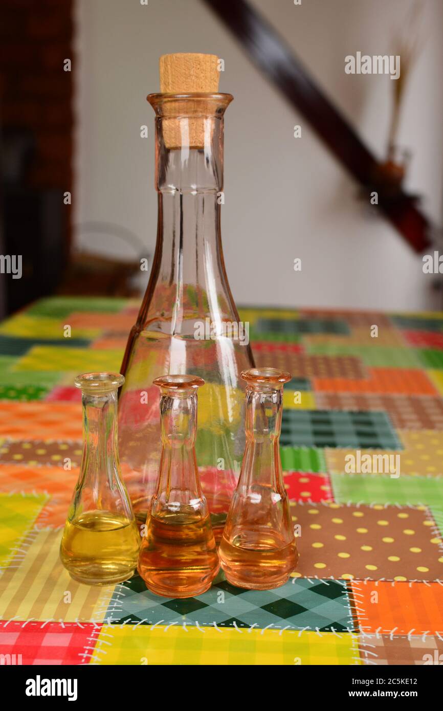 Vieille bouteille de prune et trois verres à liqueur sur la table recouverts d'un chiffon à huile mouchetée, vue latérale Banque D'Images