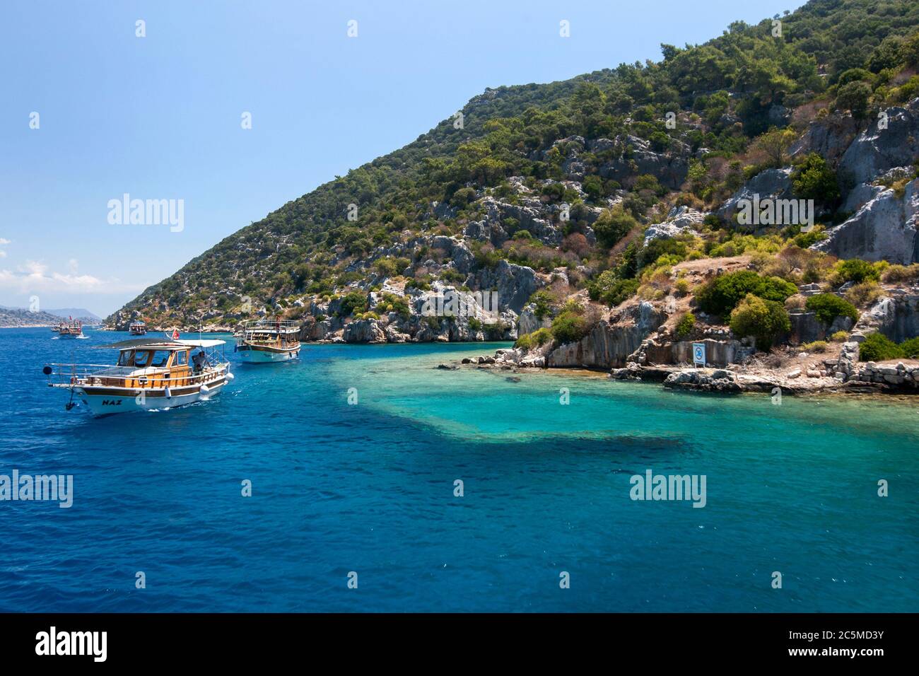 Des bateaux de croisière naviguent devant une section de la ville submergée sur l'île Kekova en Turquie. La ville est tombée dans la mer Méditerranée après une série de tremblements de terre Banque D'Images